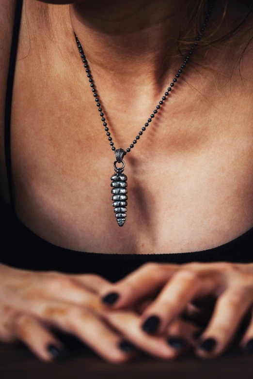 a woman's black manicured nails holding a necklace