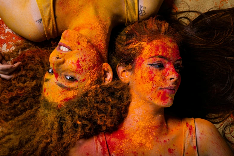 two people are covered in orange powder on their faces