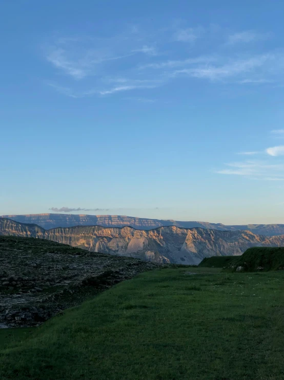 a green field in the middle of mountains