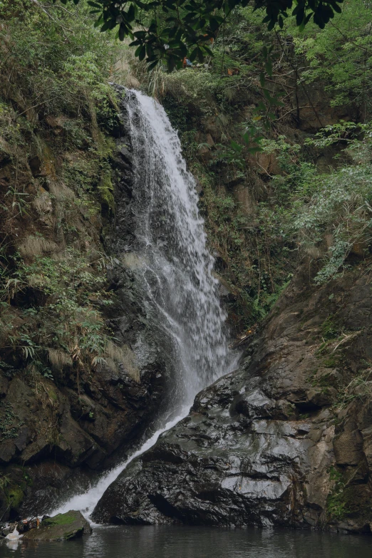 waterfall with several people in the water near rocks