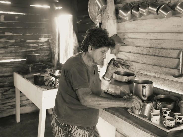 an old woman cooking in a wood cabin