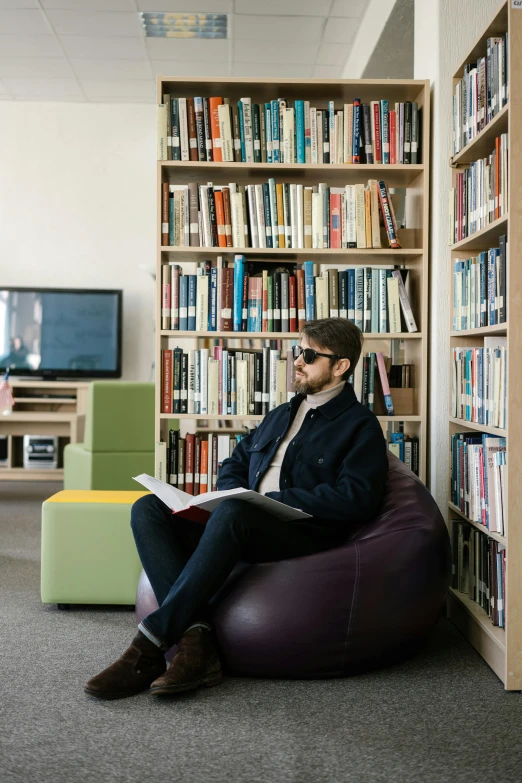 a man is reading in front of bookcases