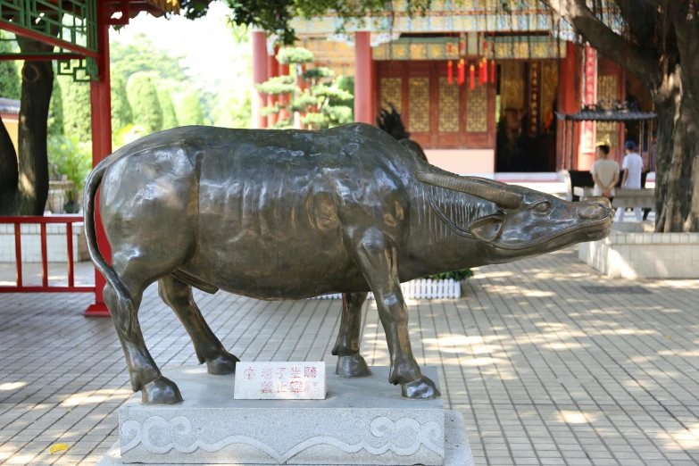 a statue of a bull stands on a pedestal in a courtyard