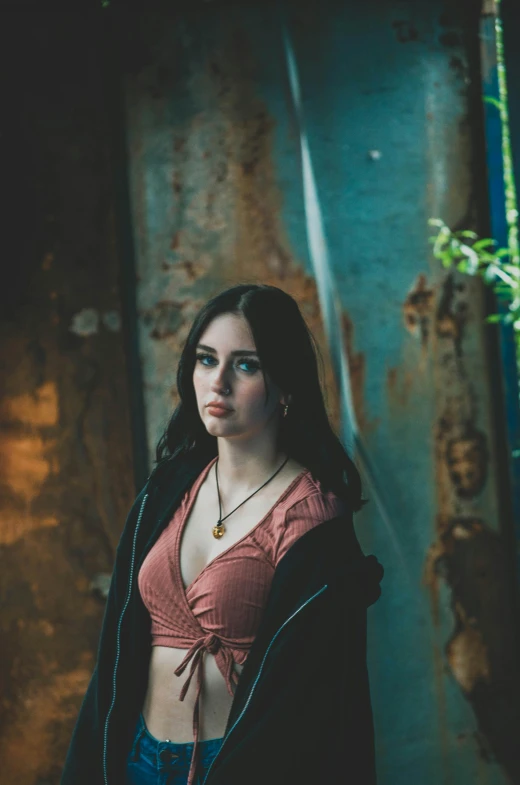 a beautiful young woman posing next to a rust wall