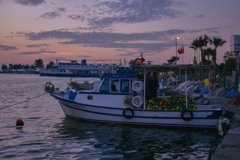 a small boat floating along the waterside at dusk