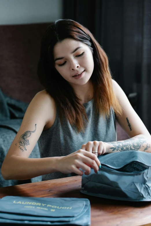 a woman holds a book while a pair of blue pants sit on a table next to her