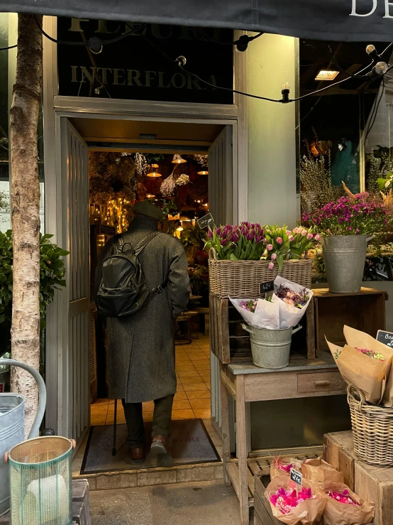 a man is entering the entrance to a store with a lot of plants in front