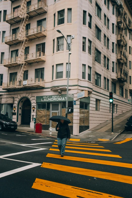 a man walking across a street under an umbrella