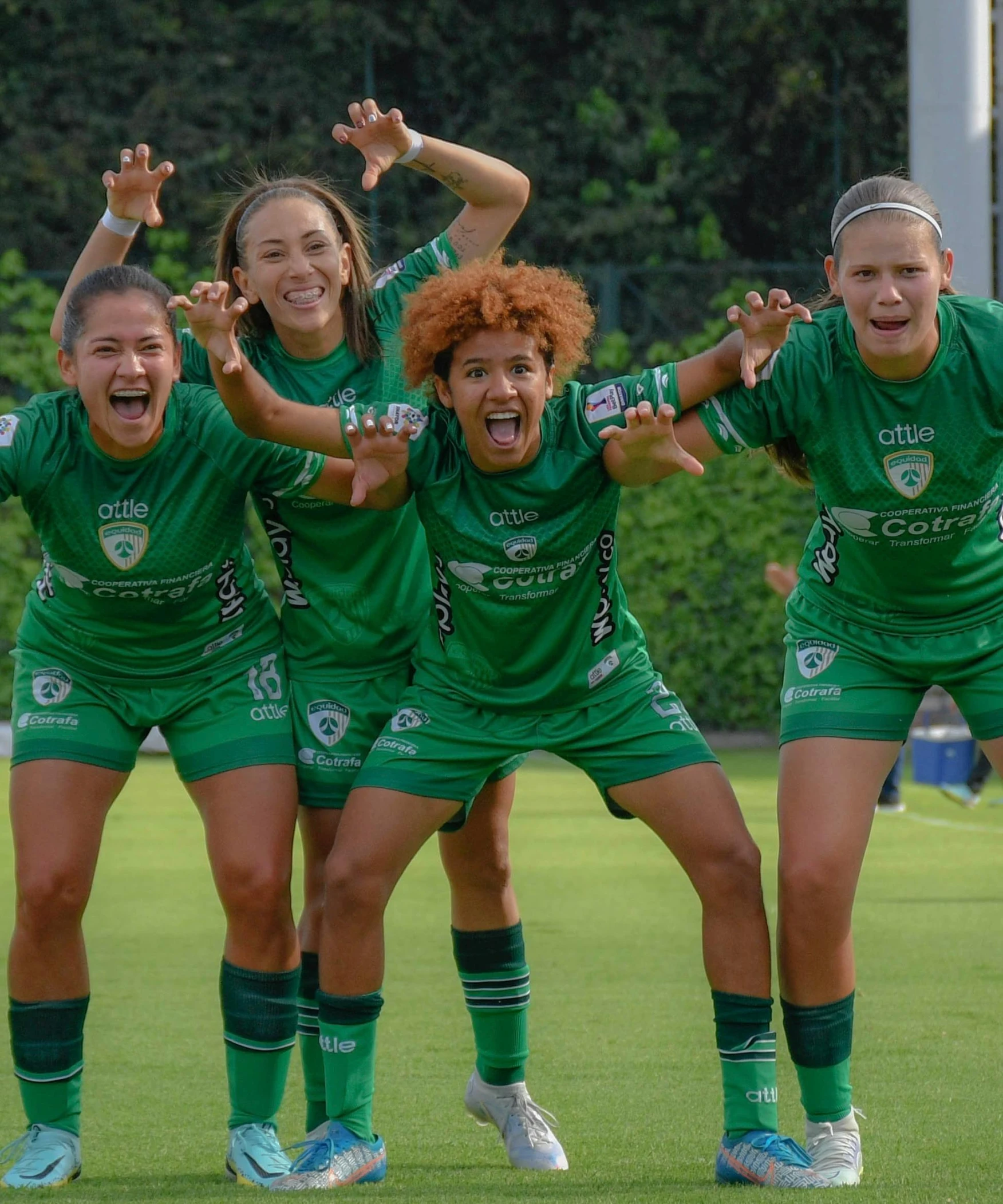 girls in green soccer uniforms with arms in the air