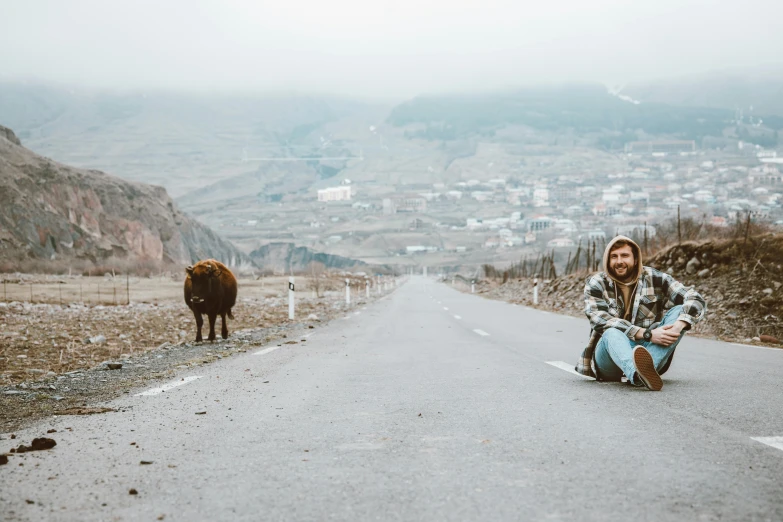 a man kneeling down on the side of an empty road