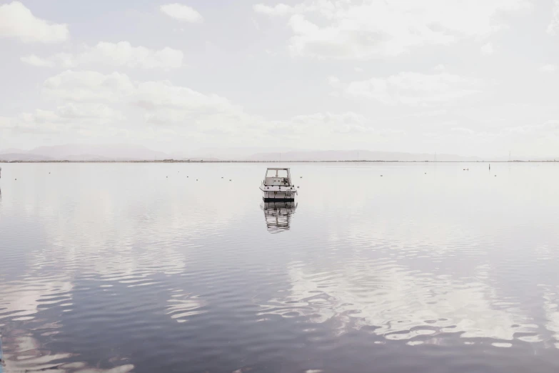 a small boat sitting in the middle of a large lake