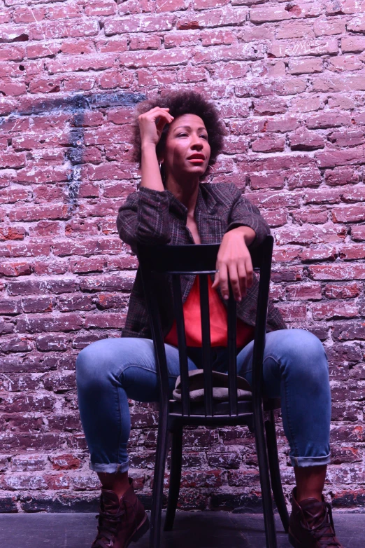 a woman sitting in a black chair next to a red wall