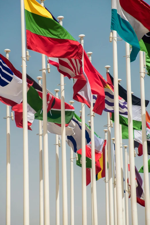 many different flags blowing in the wind on a flagpole