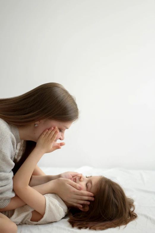 a mother hugging her daughter's chest on top of a bed