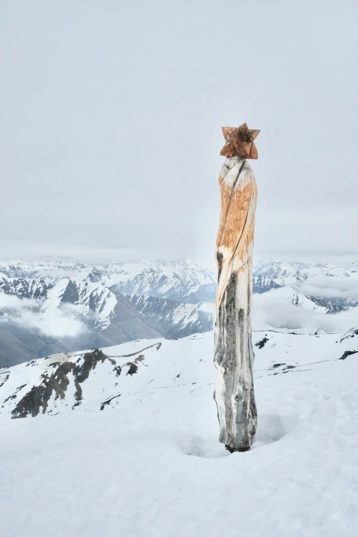 an owl sculpture stands in the snow on a mountain