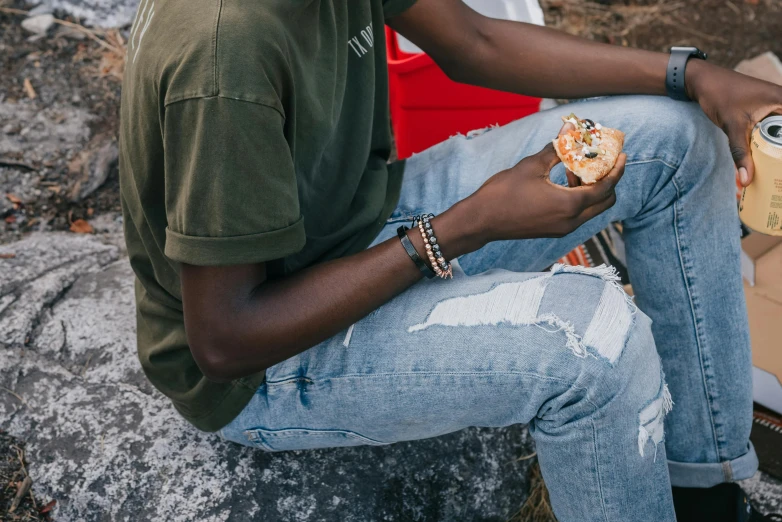 a man sitting on a pile of concrete with a pastry