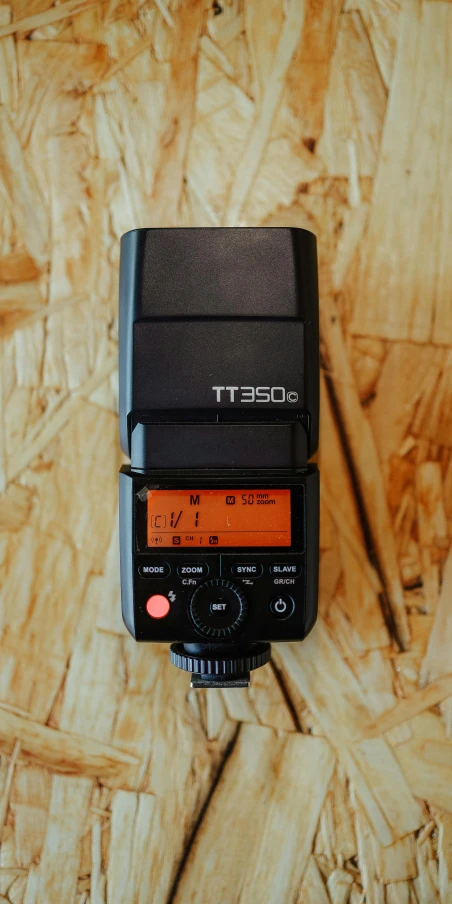 an electronic camera sitting on a table on top of a wooden floor