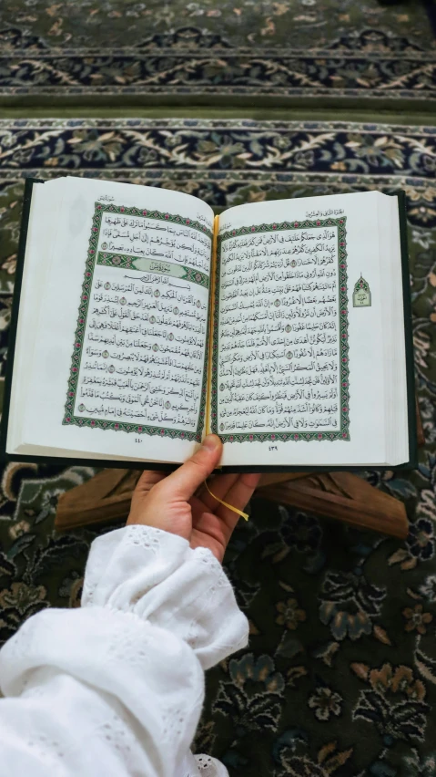 a person holding a book with arabic writing on it