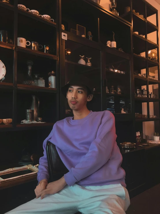 a person sitting on a bench by some shelves