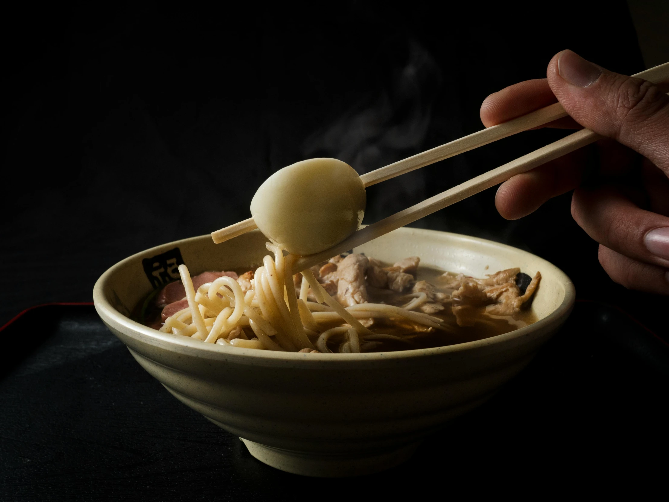 person holding a spoonful of chopsticks that are sticking out of food in a bowl