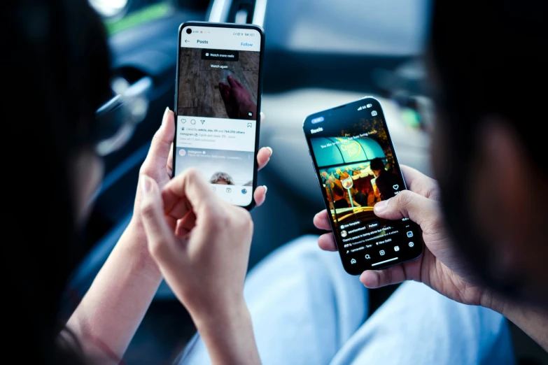 two people holding up their cell phones in their hand