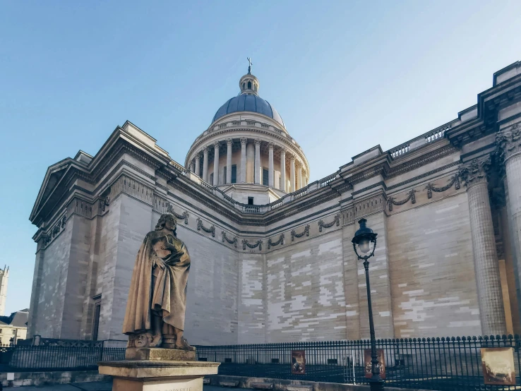 a statue in front of a tall building with a dome