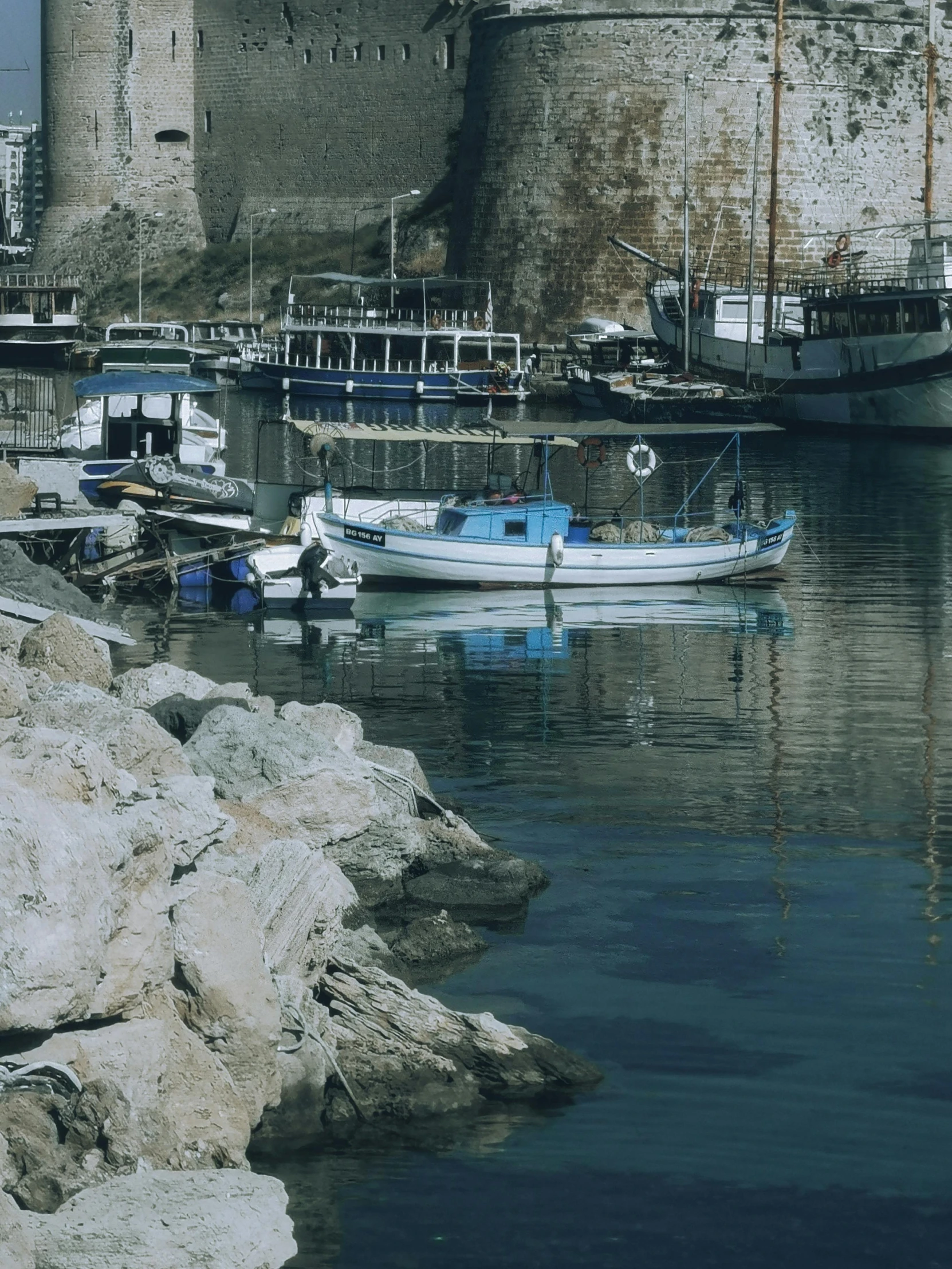 two boats tied to a shore near some rocks