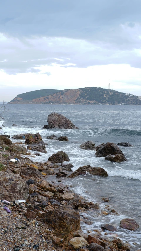 a person walking with an umbrella along the shore near water