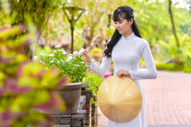 a young asian woman is holding a parasol and a small potted plant