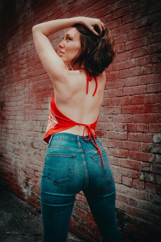 a woman with her shirt tied over her shoulders and panties in front of a brick wall