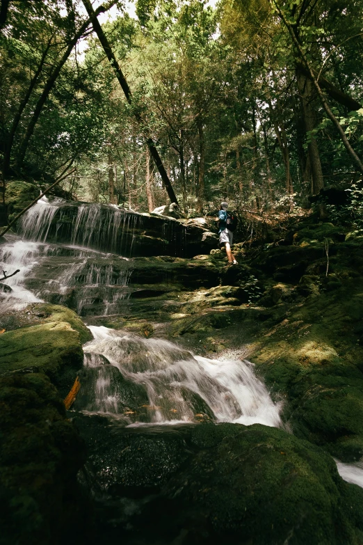 a person standing on a rock in the middle of a waterfall