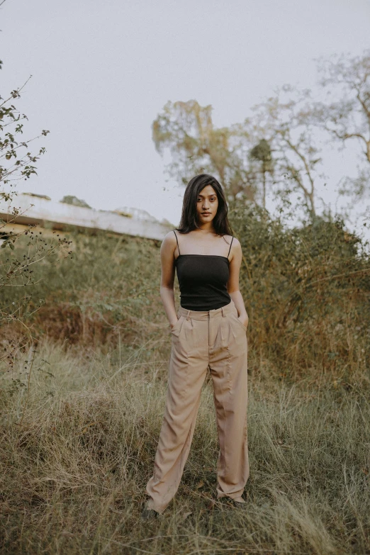 a woman in wide legged trousers and a strapless top stands outdoors