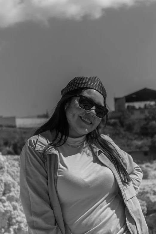 woman wearing sunglasses and jacket standing outside in desert