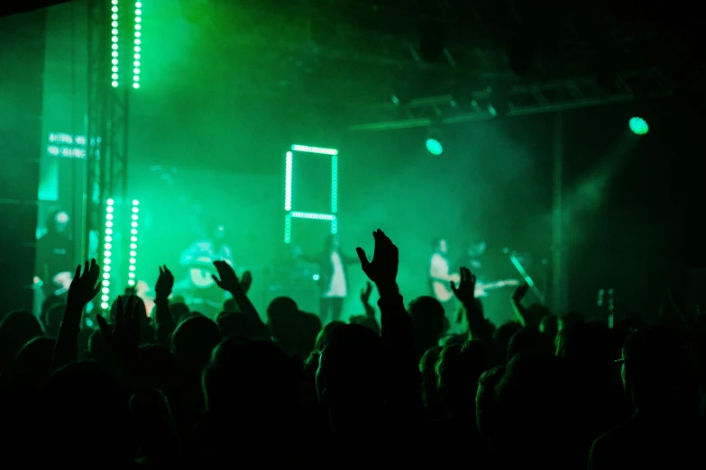 a large crowd with their hands raised up at a concert