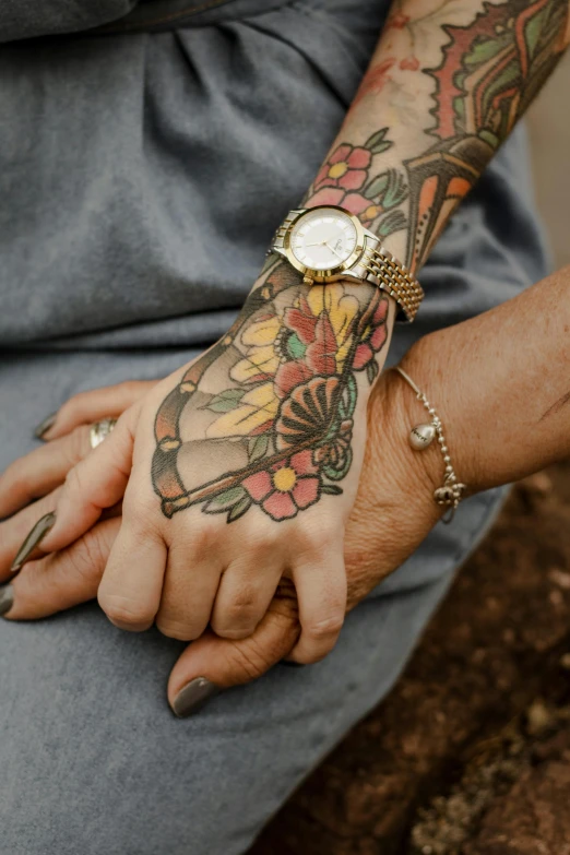 closeup of woman's arm with tattoo, wrist watch, and celet