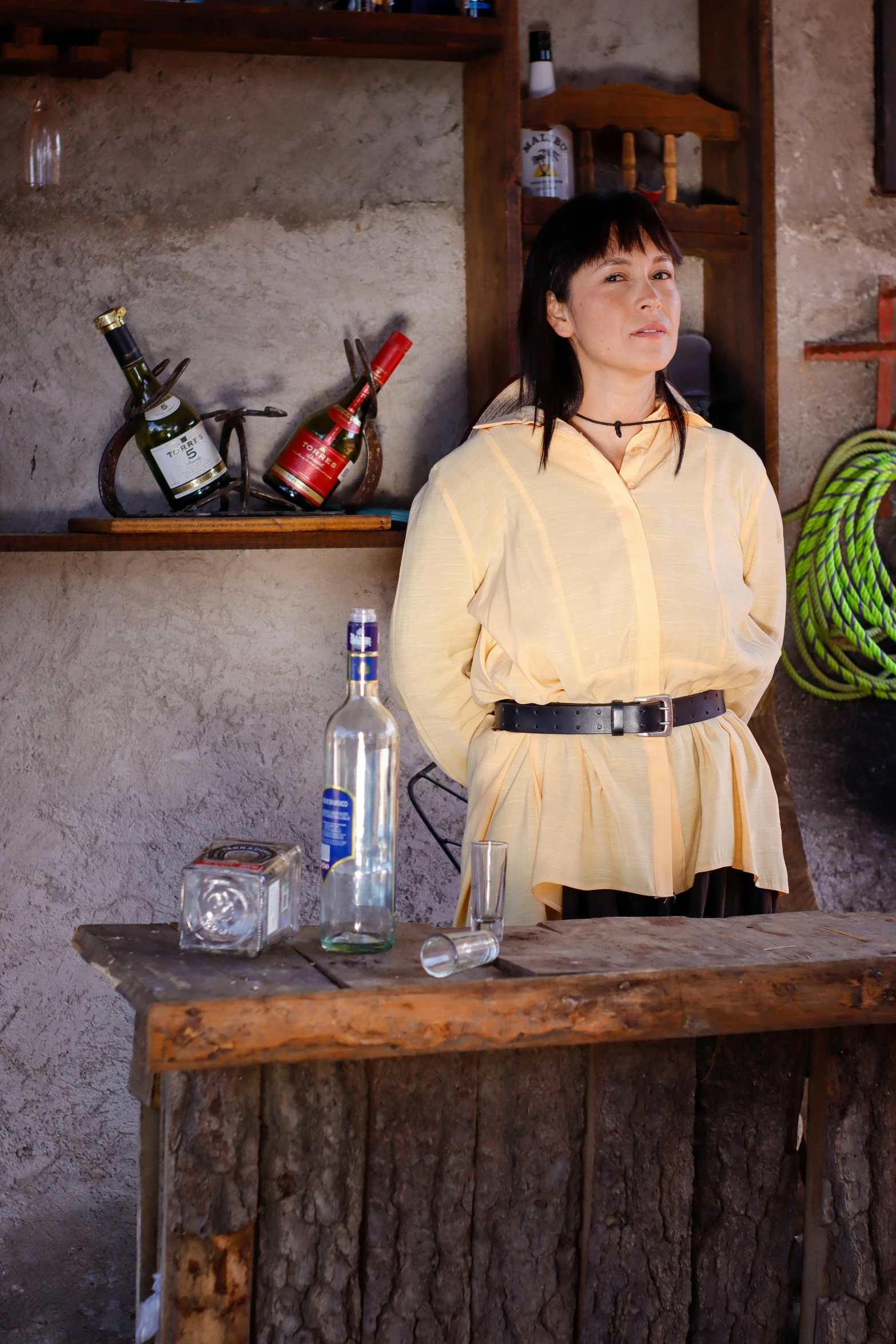 a woman posing in front of a table with a bottle