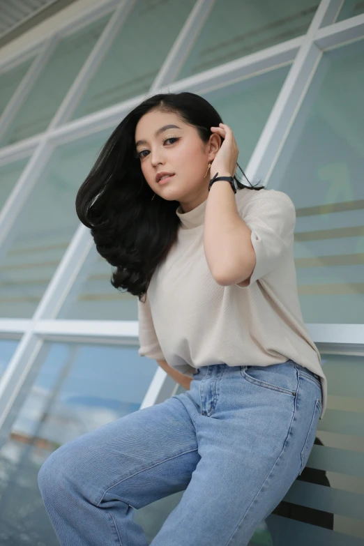 a lady wearing jeans leaning against a building with her hair in rollers