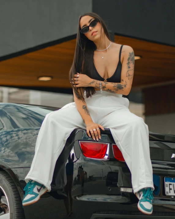 a woman sitting on the back of a black car