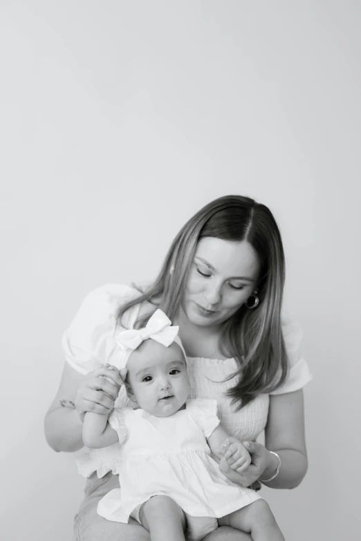 a beautiful woman holding a baby girl while she is sitting down