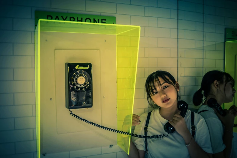 a woman holding a telephone up to the wall with two phones above her