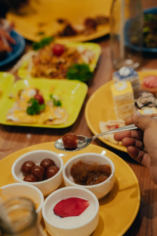 a person holding a spoon in their hand over a bowl of food