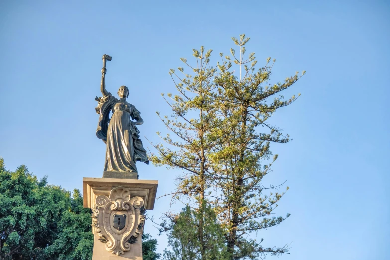 the statue of justice in the foreground is on display with a tree in the background