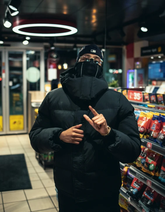 a man wearing a black winter coat and hood standing inside a grocery store