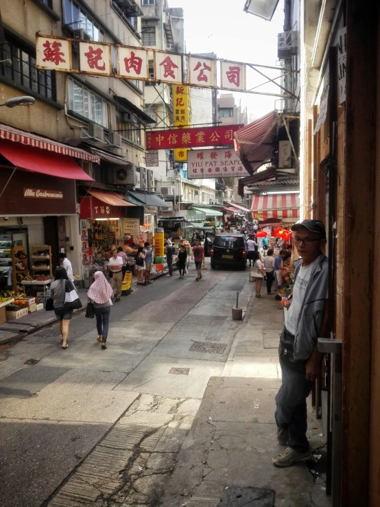 people walk down an old street near businesses