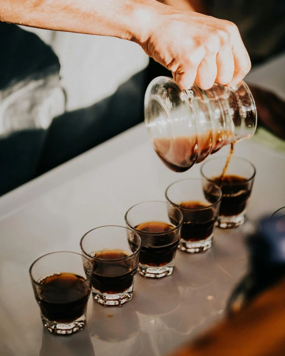 someone pours soing into small glasses to be drank