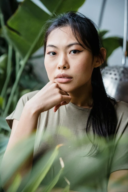 a woman sitting on top of a chair next to a plant