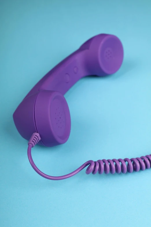 a purple old fashioned telephone sits on a light blue background