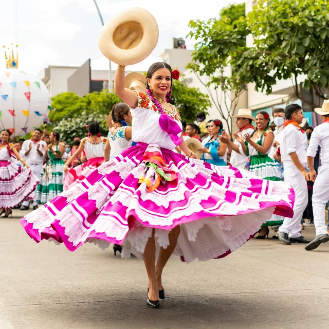 a woman in a colorful dress and hat walks with other people