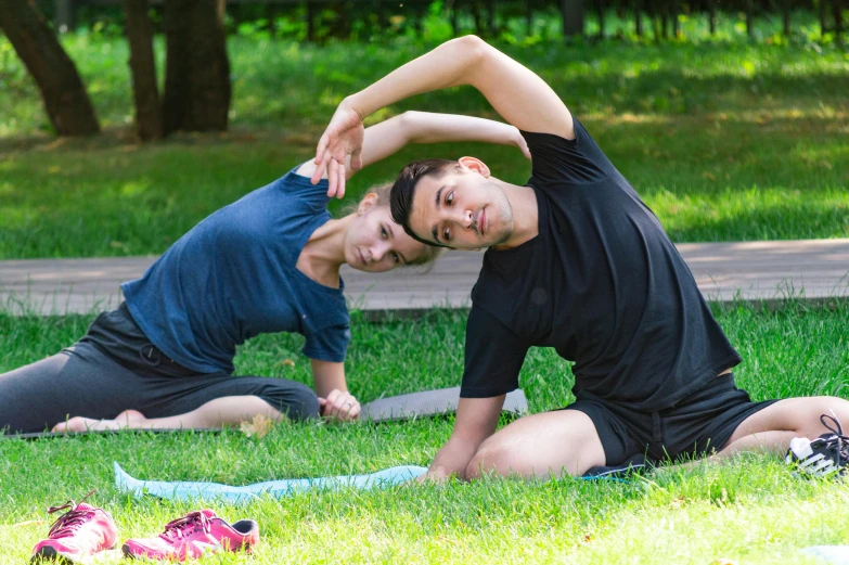 two women doing yoga in the grass near the woods