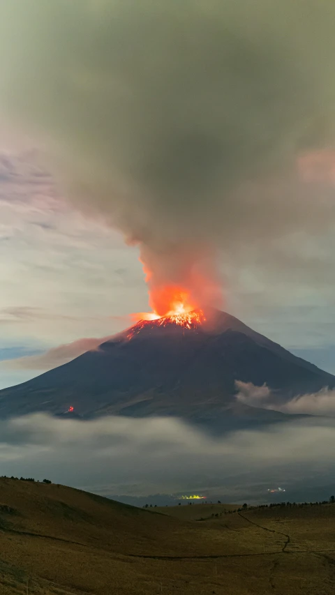 a volcano in a field is engulfed in thick smoke